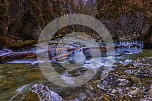 Landscape with a mountain river with small waterfalls in winter day in the canyon