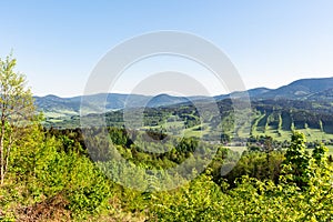 Beautiful landscape in the mountains. Blue sky, green grass and trees and in the background mountains on the horizon