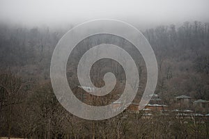 Beautiful landscape of mountains and forest with village building or old abandoned ruined brick house. Foggy forest and old buildi