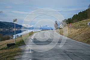 Beautiful landscape with norwegian road near fjord, mountains at background.. Spring in Norway.