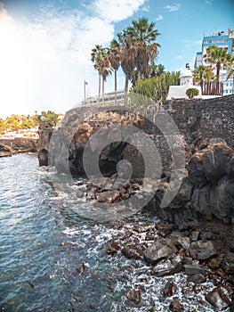 Beautiful landscape of ocean coast with high cliffs, palm trees and modern buildings