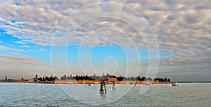 Beautiful landscape with old San Michele cemetery island in background in the Venetian Lagoon with cloudy blue sky in Venice, Ital