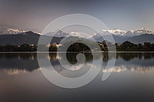 Beautiful landscape with Phewa Lake and mountains in background also as reflectaion on lake.  Machapuchare-FIshtail, Annapurna and photo