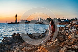 Beautiful landscape picture of a lighthouse and a woman looking the sunset