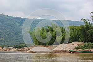 Beautiful landscape of piles of stones on the bank of river and mountain in background in Sunamgonj, Bangldesh