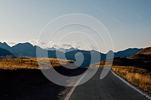 Beautiful landscape with road and mountain range silhouette in the Alps during sunset photo