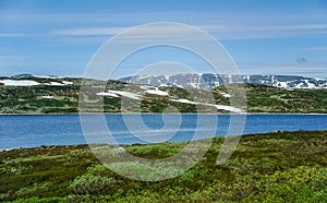 Beautiful landscape and scenery of Norway, the hills and mountain covered partially with white snow and blue lake