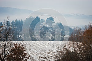 Beautiful landscape with small house on hill, snow and fog photo