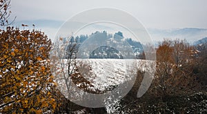 Beautiful landscape with small house on hill, snow and fog photo