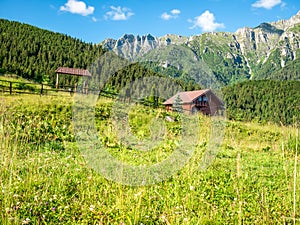 Beautiful landscape with a small wooden house and Bucegi Mountains in the background