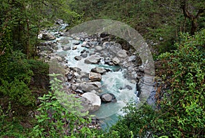 Beautiful landscape with a stormy mountain river of blue color in the jungle of Nepal, on a cloudy day