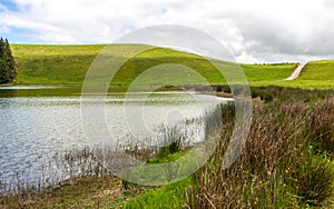 Beautiful landscape on a sunny cloudy day, with a lake, road, hills and plants