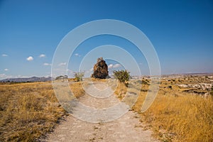 Beautiful landscape in Sunny weather. The road in the field, in the distance an unusual rock. Cappadocia, Turkey