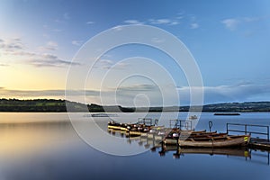 Beautiful landscape sunrise over still lake with boats on jetty