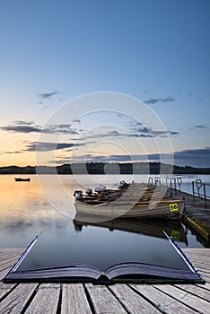 Beautiful landscape sunrise over still lake with boats on jetty