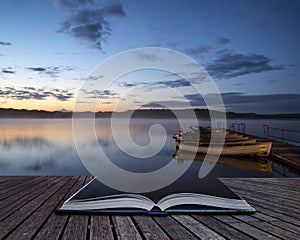 Beautiful landscape sunrise over still lake with boats on jetty