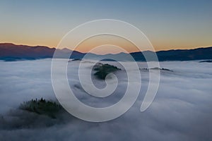 Beautiful landscape with thick mist in mountains at sunset. Drone photography