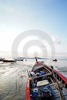 Beautiful landscape of tropical coast during outflow with traditional long tail boats, Phuket island, Thailand. Sunrise