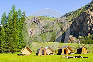 Beautiful landscape of valley in Altai mountains, small houses for tourists, majestic picturesque view in sunny day