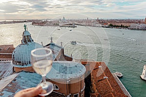 Beautiful landscape of Venice with canals and historical churches under blue sky. And glass of wine over italian city