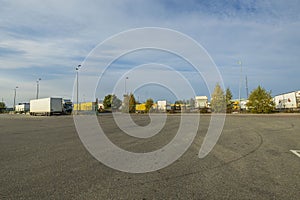 Beautiful landscape view of DHL logistic terminal. Trucks parked on huge territory on blue sky with white clouds background.