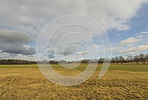 Beautiful landscape view with fields, forest trees and blue sky with white clouds. Gorgeous spring backgrounds.