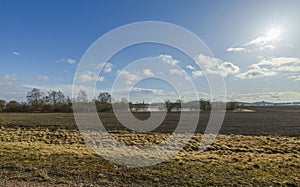 Beautiful landscape view with fields, forest trees and blue sky with white clouds. Gorgeous spring backgrounds.