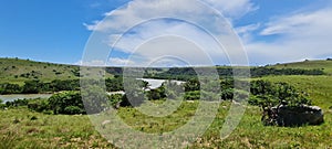 Beautiful landscape view with green fields and lake water against a cloudy sky