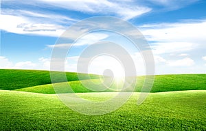 Beautiful landscape view of Green grass natural meadow field and little hill with white clouds and blue sky.