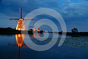 Beautiful landscape view with a row of Dutch windmills near the canal in the evening