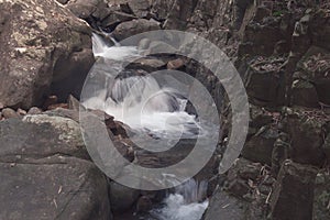 Beautiful landscape view of small waterfall in the river with water stream flowing through stone located in rainforest.