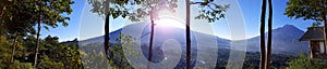 Beautiful landscape of volcano mountain during sunny day morning with forest in foregound and blue sky in background