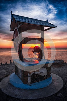 Beautiful landscape of a well with a wheel in the sunrise near the Razelm Lake