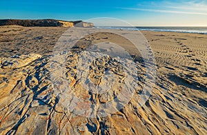 Beautiful landscapes of the Pacific coast, beach with human footprints, rocks, waves, sky, sun. Santa Cruz and Davenport