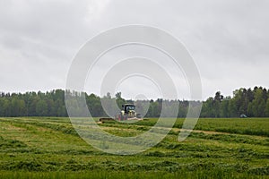 Beautiful lansdscape with haymaking is mowing the grass