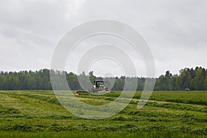 Beautiful lansdscape with haymaking is mowing the grass photo