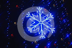 Beautiful large blue decorative shiny glowing snowflake on a dark background. Evening festive Christmas illumination