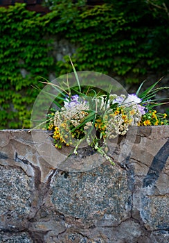 Beautiful large bouquet of flowers wreath lies on the stones of the parapet on the background of the green of Ivan Kupala
