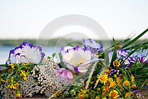 Beautiful large bouquet of flowers wreath lies on the stones of the parapet on the background of the river Ivan Kupala