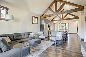 Beautiful large bright vaulted ceiling with large wooden beams and white walls living room interior with stone and leather sofa