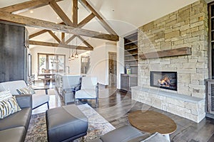 Beautiful large bright vaulted ceiling with large wooden beams and white walls living room interior with stone and leather sofa