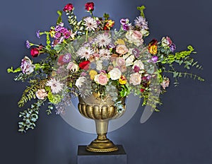 A Beautiful large flower bouquet with a lot of different flowers in a golden pot