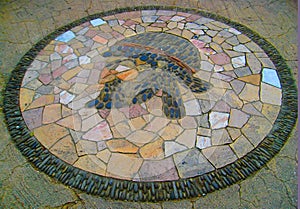 Beautiful large patterned pebble stone mosaic arranged in a symbol on pavement pedestrian street in Nice, Cote d`Azur, France