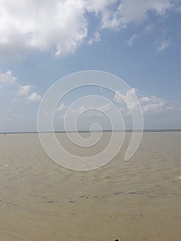 A beautiful large river of brakish water under clear blue sky  and some white cotton  clouds are floating across the sky . photo