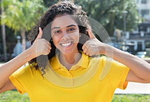 Beautiful latin american girl with long dark hair showing both thumbs