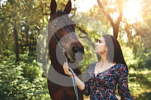 Beautiful Latin woman in dress and her lovely horse walk in the forest. love animals concept. love horses