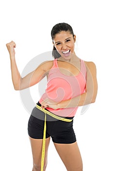 Beautiful latin woman in fitness clothes measuring body waist size holding measure tape smiling happy