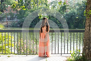 Beautiful latin woman with long curly hair poses as a model dressed in an elegant dress with flowers and shiny stones. In the