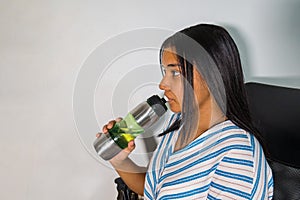 Beautiful Latina Hispanic young woman drinking water bottle at home