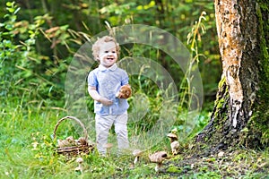 Beautiful laughing baby girl having fun gathering mushrooms